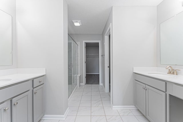 bathroom with vanity, a shower with shower door, and a textured ceiling