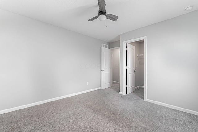 unfurnished bedroom with a walk in closet, carpet, ceiling fan, and a closet