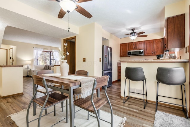 dining room featuring ceiling fan, a textured ceiling, and light wood-type flooring