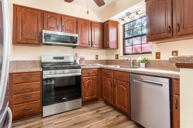 kitchen with ceiling fan, appliances with stainless steel finishes, sink, and light wood-type flooring