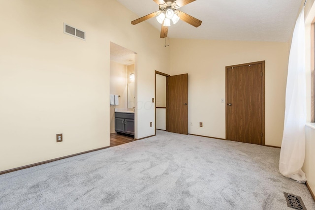 unfurnished bedroom featuring ensuite bathroom, carpet, ceiling fan, and high vaulted ceiling