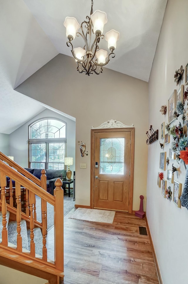 foyer with an inviting chandelier, lofted ceiling, and light hardwood / wood-style flooring