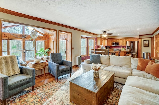 living room with ornamental molding, hardwood / wood-style floors, ceiling fan, and a textured ceiling