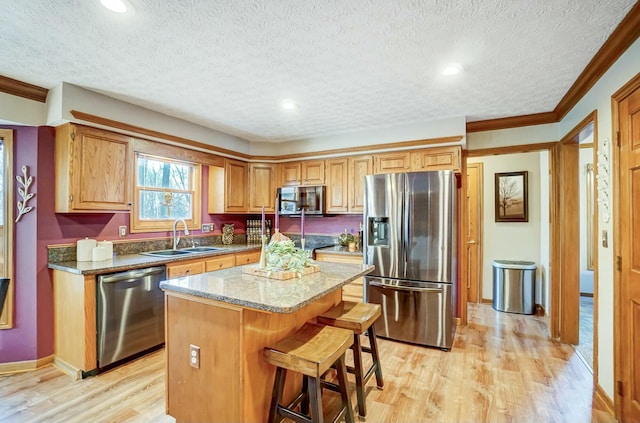 kitchen with appliances with stainless steel finishes, a center island, sink, and light hardwood / wood-style flooring