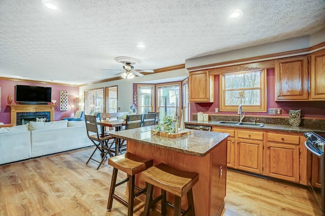 kitchen with sink, a breakfast bar area, stainless steel appliances, a kitchen island, and light wood-type flooring