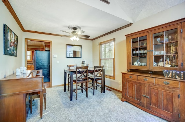 dining area with ceiling fan, light colored carpet, and a textured ceiling