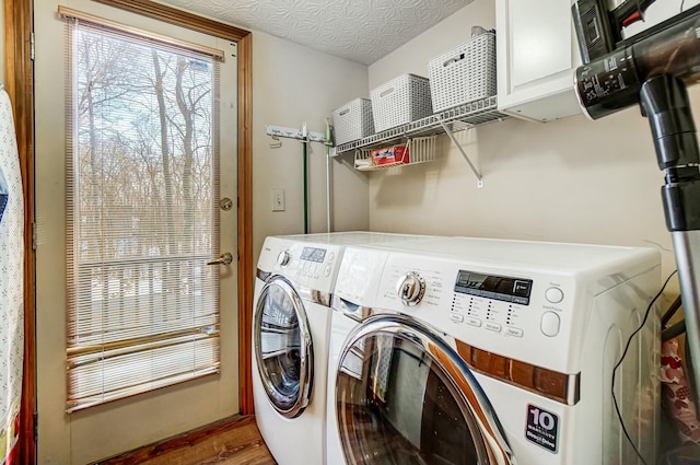 laundry room with a textured ceiling, wood-type flooring, and washing machine and clothes dryer