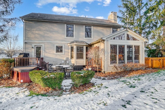 snow covered property with a hot tub and a wooden deck