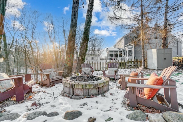 snow covered patio with a shed and a fire pit