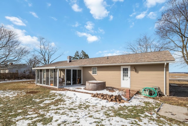 snow covered rear of property with a sunroom