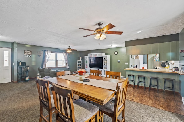 dining space featuring ceiling fan, dark carpet, and a textured ceiling