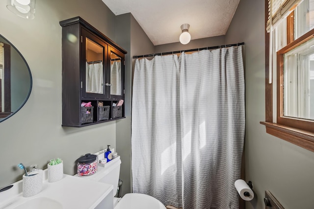 bathroom with a textured ceiling, toilet, and a shower with shower curtain