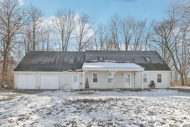 snow covered rear of property with a porch and a garage