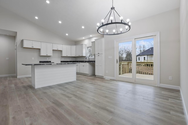 kitchen featuring hanging light fixtures, a center island, white cabinets, and high vaulted ceiling