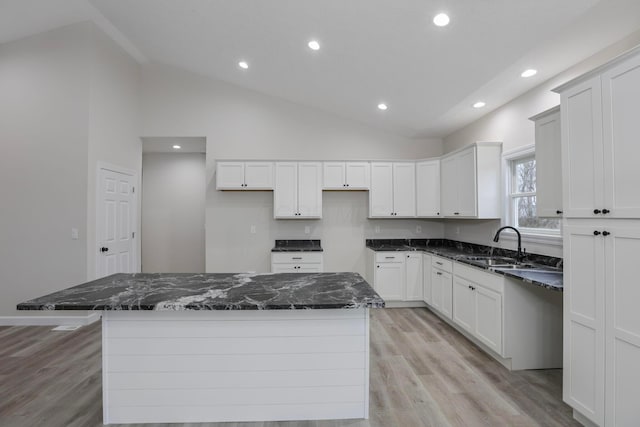 kitchen featuring sink, high vaulted ceiling, dark stone counters, and a kitchen island