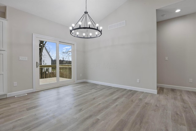 unfurnished dining area with a notable chandelier, vaulted ceiling, and light wood-type flooring