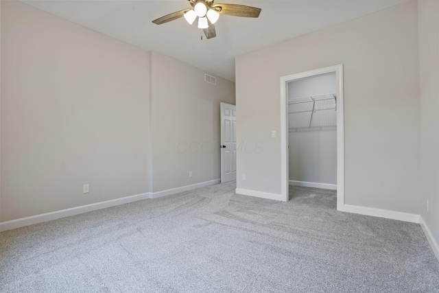 unfurnished bedroom featuring ceiling fan, a spacious closet, carpet floors, and a closet