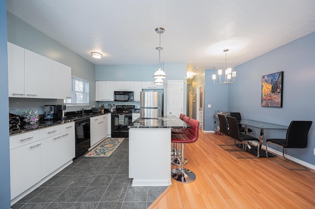 kitchen with pendant lighting, white cabinetry, black appliances, and a center island