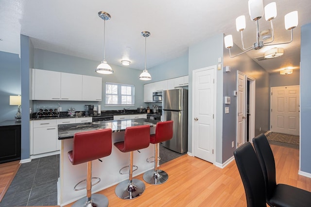 kitchen featuring pendant lighting, a breakfast bar area, white cabinets, stainless steel fridge, and a center island