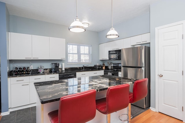 kitchen with white cabinetry, a kitchen island, a kitchen breakfast bar, and black appliances