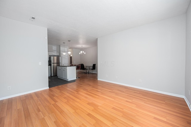674 Park St, Columbus, OH 43215 - unfurnished living room featuring light wood finished floors, baseboards, and a chandelier