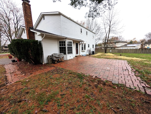 rear view of house featuring central AC unit, a lawn, a chimney, fence, and a patio area