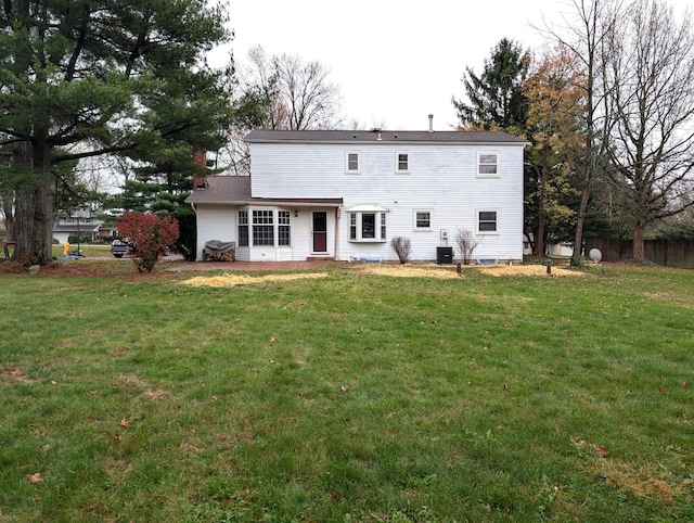 rear view of property featuring cooling unit, a yard, and fence