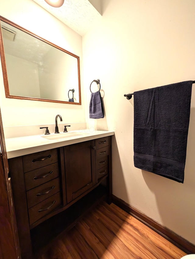 bathroom featuring baseboards, wood finished floors, and vanity