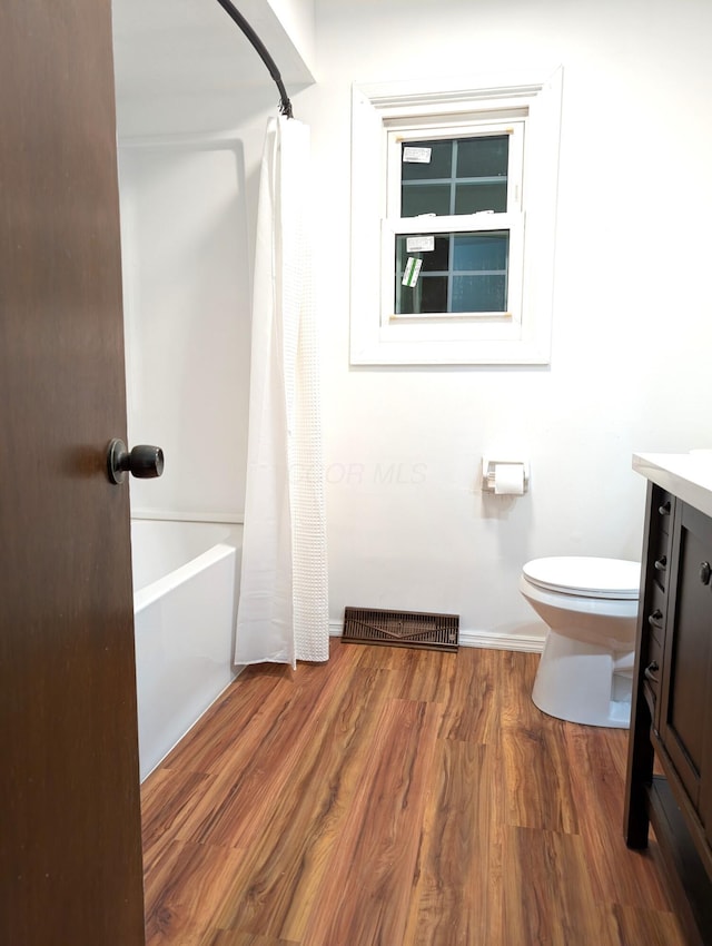 full bathroom with baseboards, visible vents, toilet, wood finished floors, and vanity