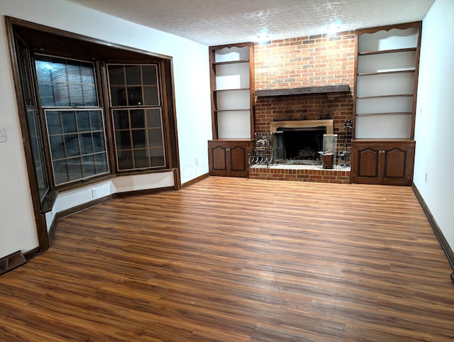unfurnished living room with visible vents, baseboards, wood finished floors, a textured ceiling, and a fireplace