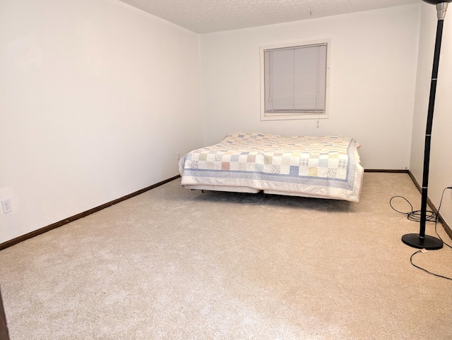 bedroom with light carpet, a textured ceiling, and baseboards