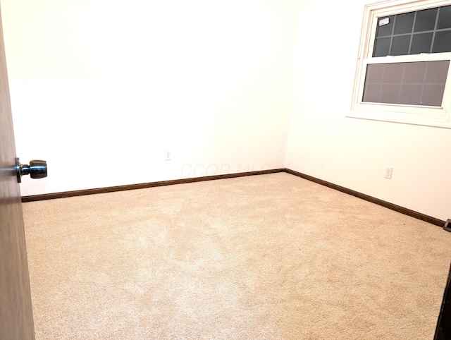 carpeted empty room featuring baseboards