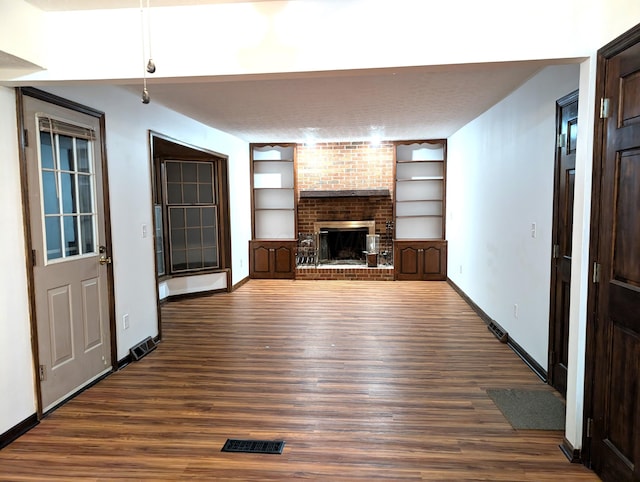 unfurnished living room featuring dark wood-style floors, a fireplace, visible vents, and baseboards