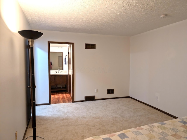 carpeted empty room featuring visible vents, a textured ceiling, and baseboards