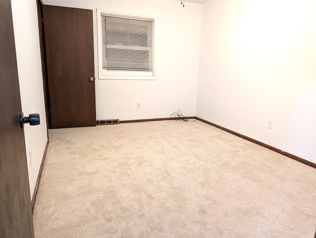 carpeted spare room featuring visible vents and baseboards