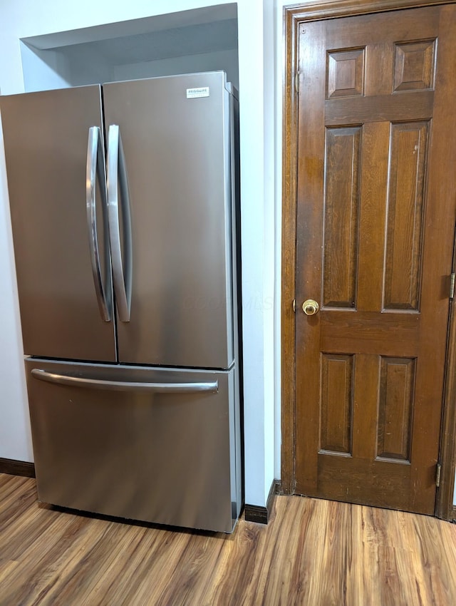 kitchen featuring freestanding refrigerator, baseboards, and wood finished floors