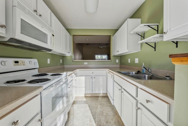 kitchen with white appliances, light tile patterned floors, sink, and white cabinets