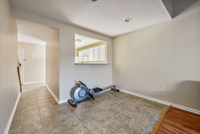 exercise room with a textured ceiling and light tile patterned floors