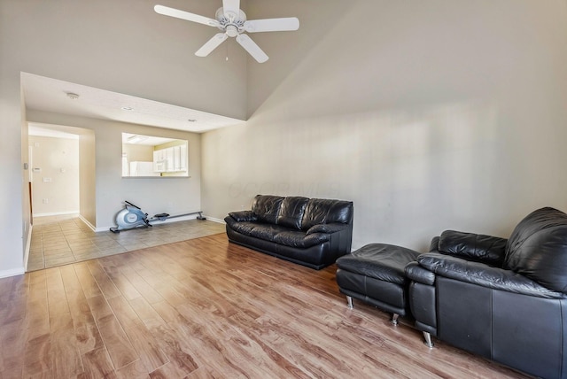 living room featuring a towering ceiling, light hardwood / wood-style flooring, and ceiling fan