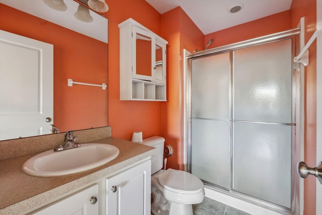 bathroom with an enclosed shower, vanity, tile patterned flooring, and toilet