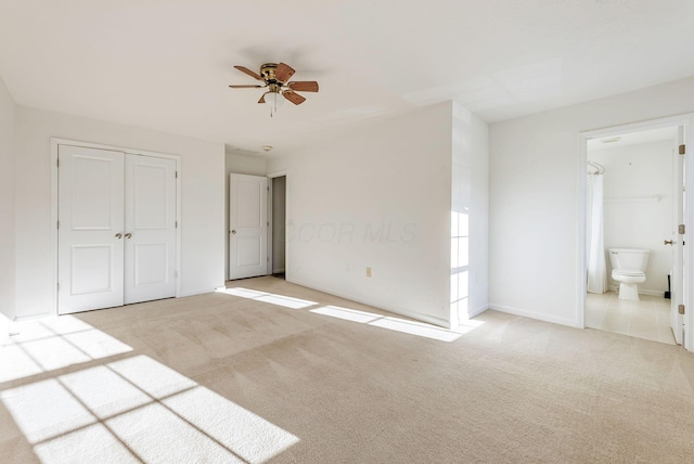 unfurnished bedroom with ceiling fan, a closet, connected bathroom, and light carpet