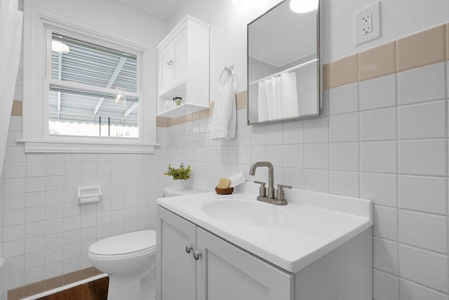 bathroom with vanity, tile walls, and toilet