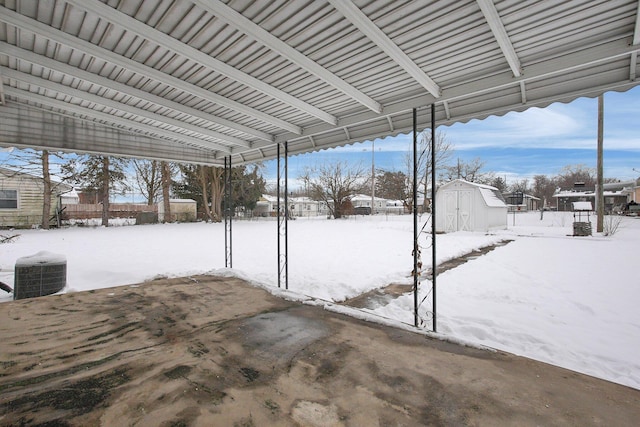 snow covered patio featuring a shed and central AC