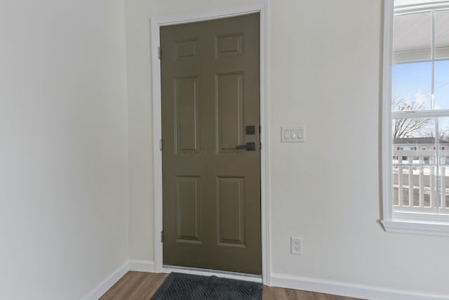 doorway with baseboards and wood finished floors