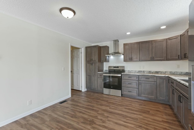 kitchen featuring visible vents, dark wood-style floors, stainless steel electric range oven, light countertops, and wall chimney range hood