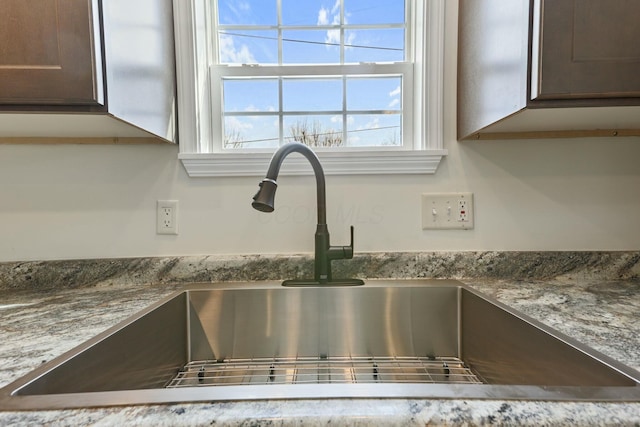 details featuring a sink and light stone countertops