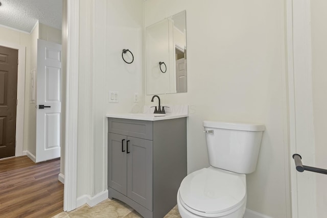 bathroom featuring a textured ceiling, toilet, wood finished floors, vanity, and baseboards