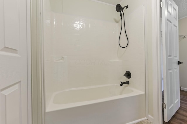 full bath featuring shower / washtub combination, wood finished floors, and baseboards