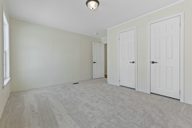 unfurnished bedroom featuring light carpet and a textured ceiling