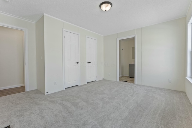 unfurnished bedroom with light carpet, a textured ceiling, and ensuite bathroom